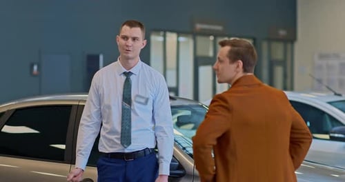 Sales Assistant of the Car Dealership Shows the Car to the Client