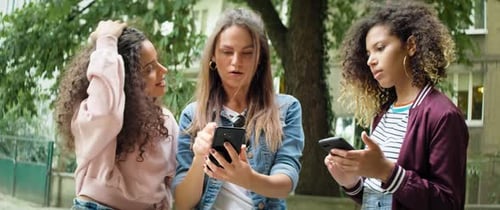 Three Young Women Looking at Cell Phones Together