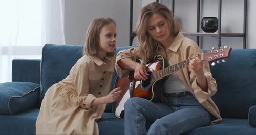 Woman and Child Play Guitar Together at Home