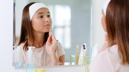 Teen Cleans Face With Cotton Pad In Mirror