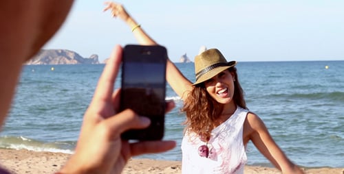 Man Photographs Woman Posing on Beach