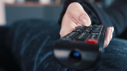 Close-Up of Hand Operating a Black Remote Control
