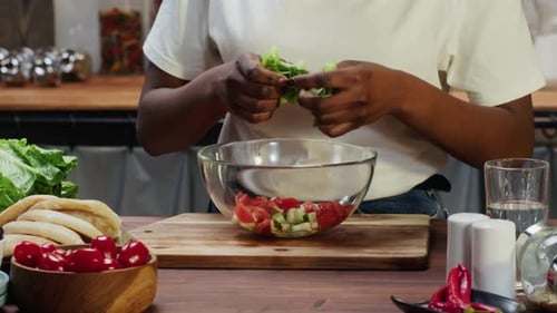 Person Tearing Lettuce for Salad at Kitchen Table