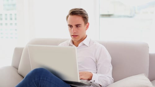 Young Man Works On Laptop on Couch