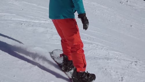 Snowboarder im rot-blauen Anzug auf einer Skipiste