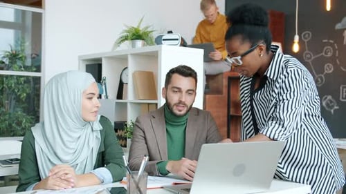 Team Collaborating on Laptop in Modern Office