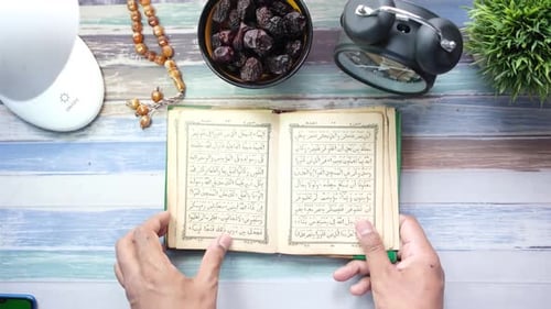 Muslimischer Mann blättert die Seiten des Holly Book of Quran von oben um