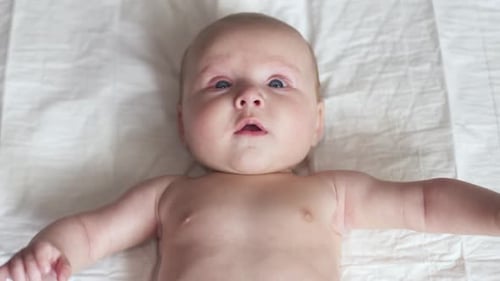 Happy Newborn Baby Toddler on Bed, Moves Hands, Smiles, Tries To Talk, Maternity