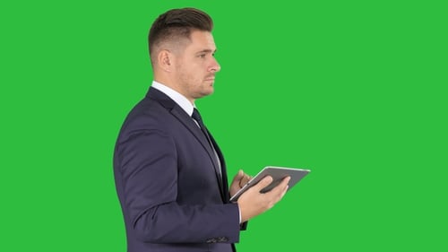Stylish Man in Suit Using Tablet on Green Screen
