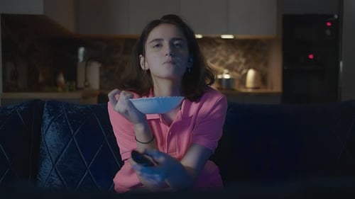 Young Woman Eats Chips While Watching Television