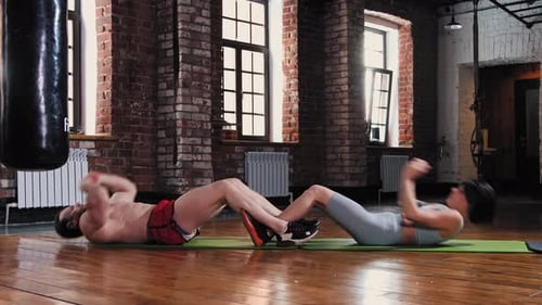 Athletic Man and Woman Pump Their Abs Together in the Gym