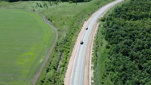 Flight a drone above highway with vehicles. Aerial view of trucks transporting cargo. Scenic road