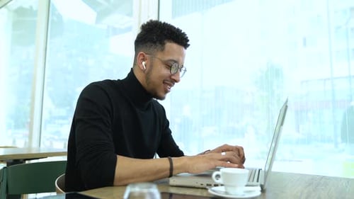 Young Adult Working on Laptop in Cafe