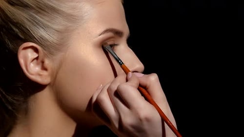 Maquillage professionnel du visage pour la prise de photos, l'artiste appliquant des ombres à paupières