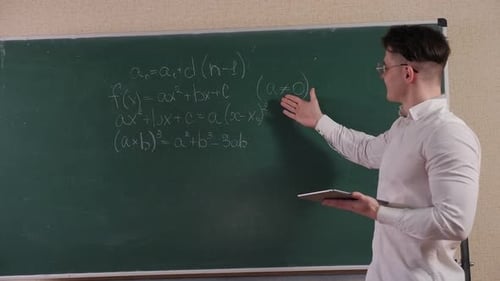Young Adult Explains Math Formula at Chalkboard