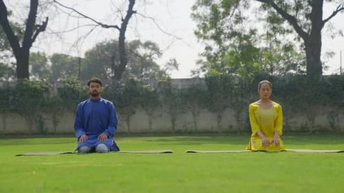 Man and Woman Meditating Outside in Lawn