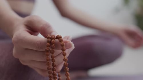Woman Meditating With Prayer Beads in Studio