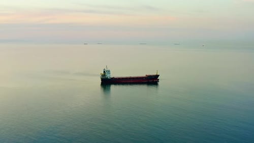Bulk Carrier Ship at Anchor in Orange Sunset Aerial View