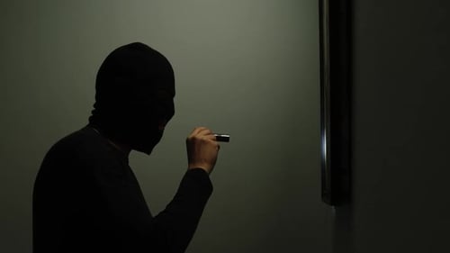 Masked Person Shines Flashlight Around Dark Room