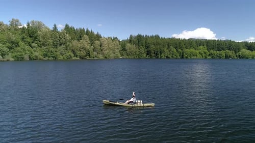 Tranquila aérea del hombre echando fuera de la pesca del lago desde kayak