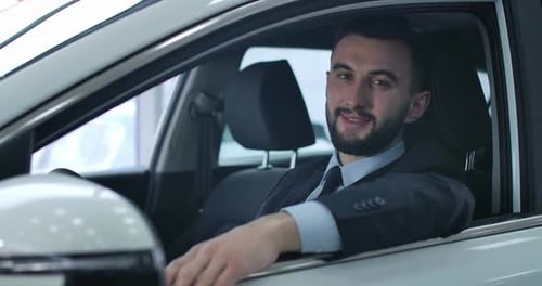 Close-up Portrait of Satisfied Caucasian Young Man Posing in Car on Driver's Seat