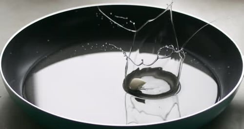 Cook Throws Garlic in Sunflower Oil on a Frying Pan Side View