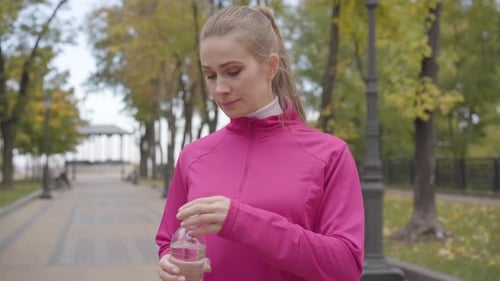 Woman Jogging and Drinking Water in Park