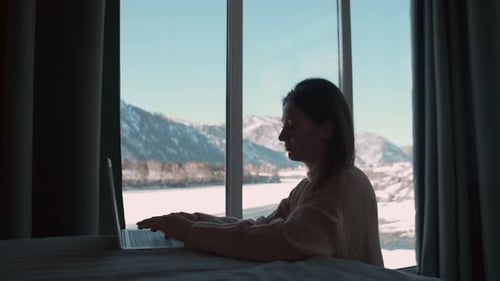 Woman Working on Laptop with Winter Mountain View