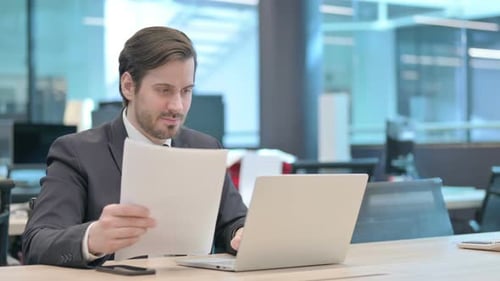 Businessman Reacts Positively to Laptop Results in Office