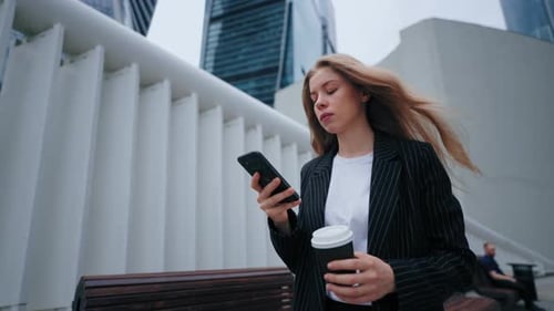 Young Woman Using Phone Holding Coffee in City