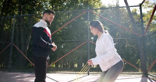 Woman Doing Resistance Band Squats With Trainer