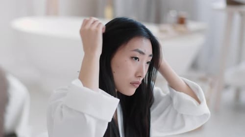 Woman Inspecting Her Black Hair in Bathroom