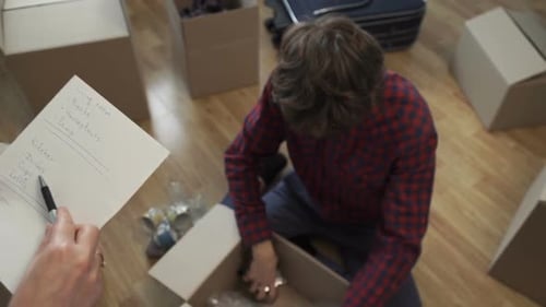 Man and Friend Packing Possessions in Cardboard Boxes