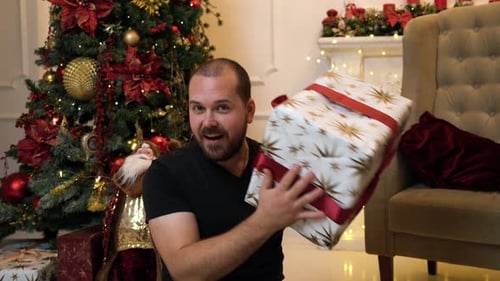 Man Holding Christmas Gift in Decorated Home