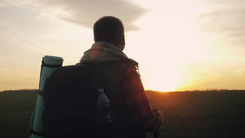 Lone Hiker Walks Into Setting Sun Landscape