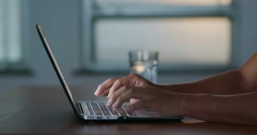 Hands Typing on Laptop Keyboard at Desk