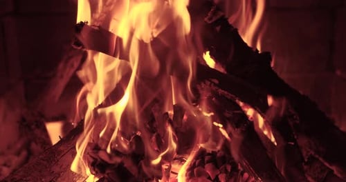 Wood Burning Slowly with Orange Fire Flame in Cozy Brickwork Fireplace Atmosphere.