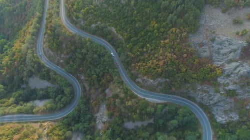 Top View From Drone Following White Truck and Car Driving Along Mountain Winding Road in Sunny