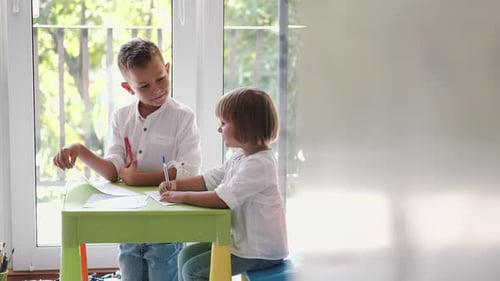 Two Young Children Drawing Together at Table