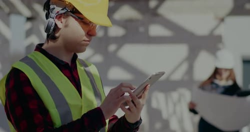 Selbstbewusster junger männlicher Bauunternehmer nutzt digitales Tablet