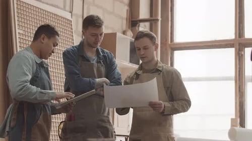 Woodworkers Looking at Drawing Plan in Carpentry Workshop