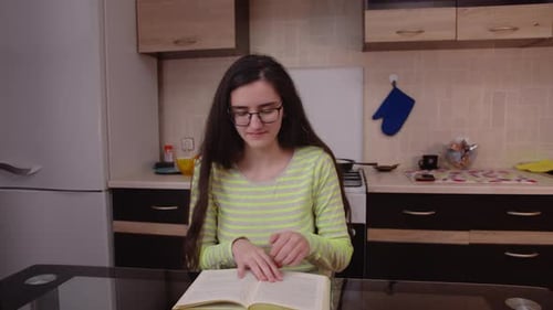 Girl student at home preparing for study, reading a textbook