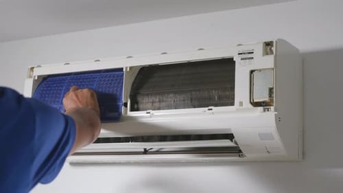 Technician placing back clean filter into air conditioner