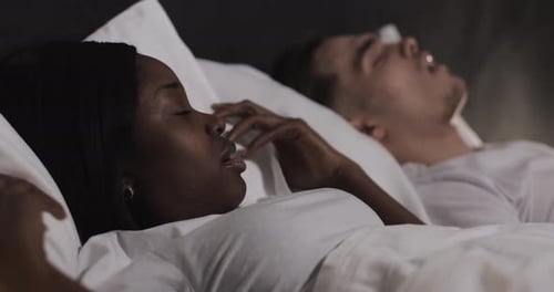 Couple multiethnique couché au lit ensemble. Une femme souffre du ronflement de son partenaire au lit
.