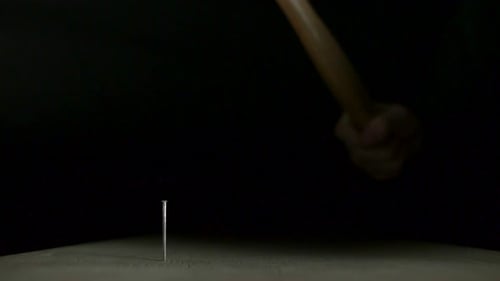 Hammer Driving Nail in Slow Motion on Black