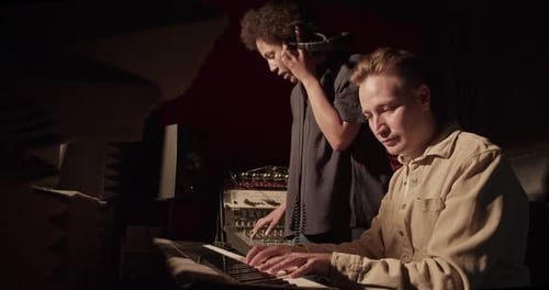 Two Young Adults Recording Music in Studio