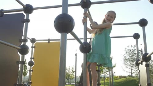Girl Climbs on Modern Playground Equipment