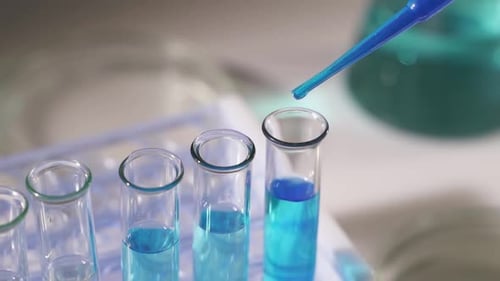 Close Up of Pipette with Liquid Blue Water Drop Intro Glass Test Tube in Laboratory
