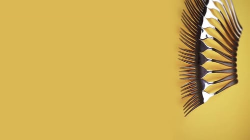 A Collection of Forks on a Yellow Background