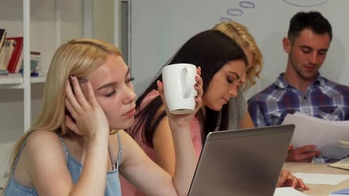 Joven empresaria que parece cansada mientras trabaja con su equipo